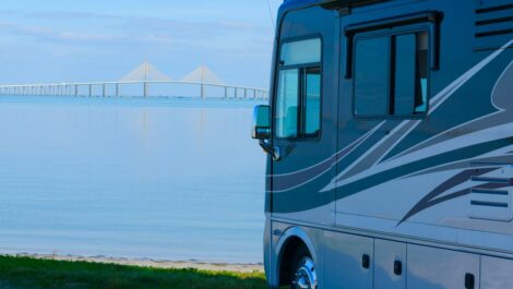 An RV parked near the water with the Skyway Bridge of Tampa Bay, FL, in the background
