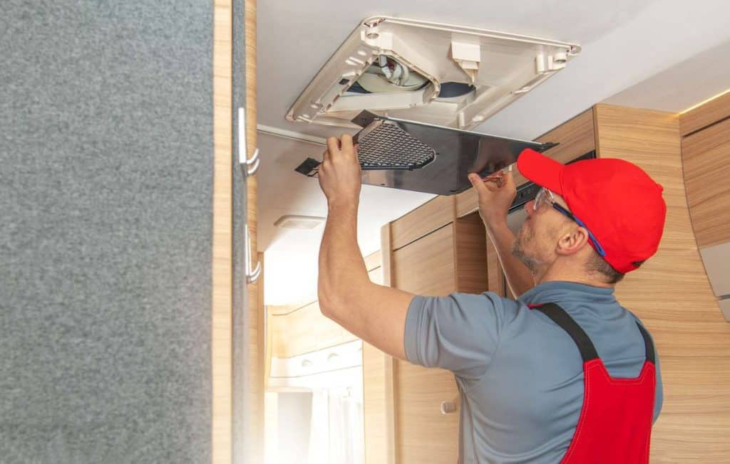 A repair man works on the electrical system inside of an RV