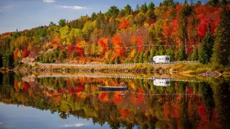RV driving through highway with colorful autumn trees in the background