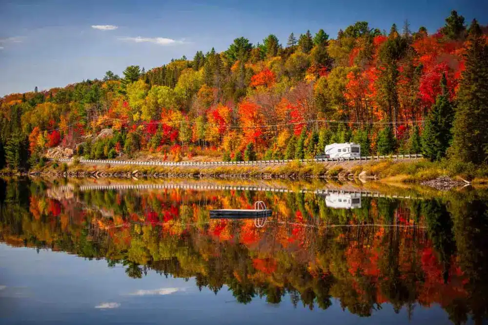 RV driving through highway with colorful autumn trees in the background