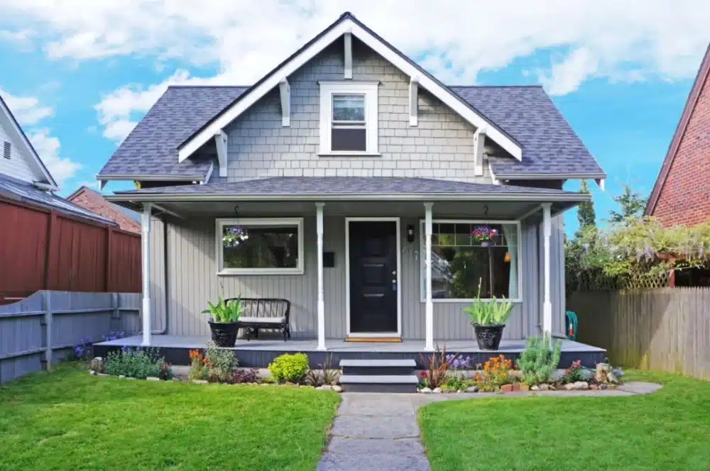 A cute, small home with a modest front porch and tasteful landscaping.