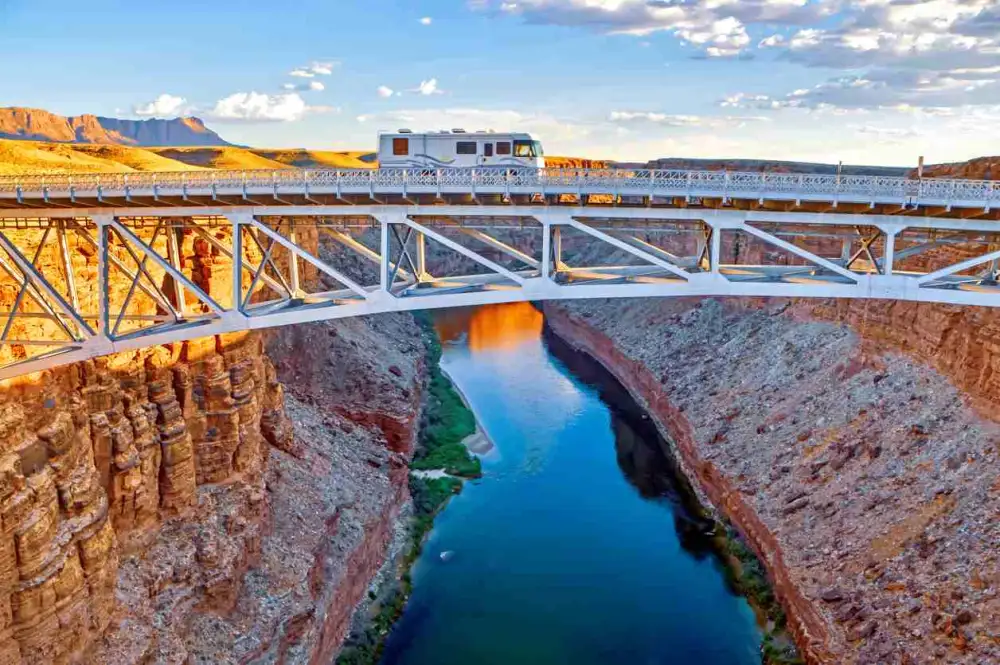 An RV drives across a bridge over a canyon