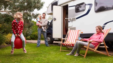A family enjoying time outside the RV they’re renting for vacation.