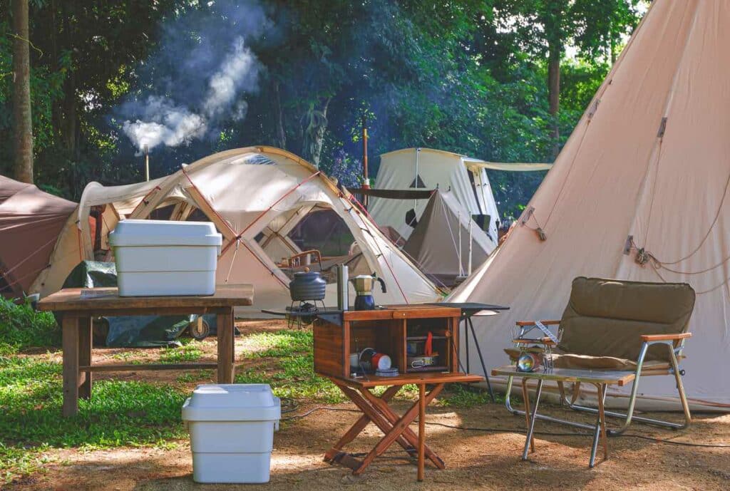 Outdoor kitchen equipment and wooden table set up at a campsite.