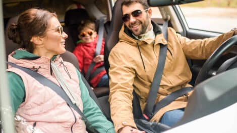 A happy family smiling in a car on a family vacation.
