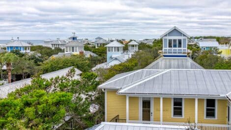 The tops of trees and houses in Seaside, FL, in winter with clouds in the sky.