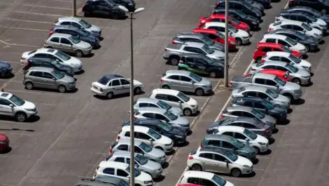 Aerial view of a crowded parking lot filled with rows of parked cars in various colors.
