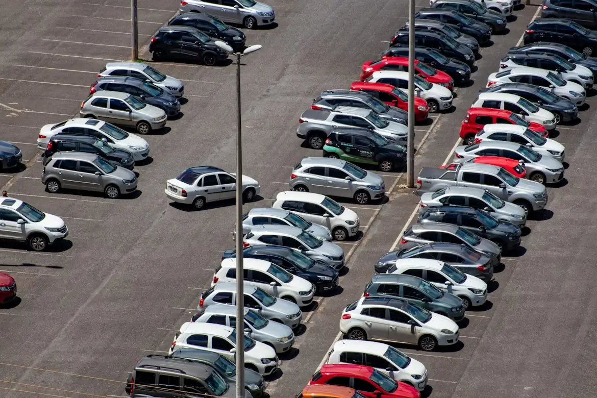 Aerial view of a crowded parking lot filled with rows of parked cars in various colors.