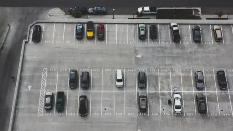 Aerial view of a mostly empty rooftop parking lot with a few scattered cars and visible numbered spaces.