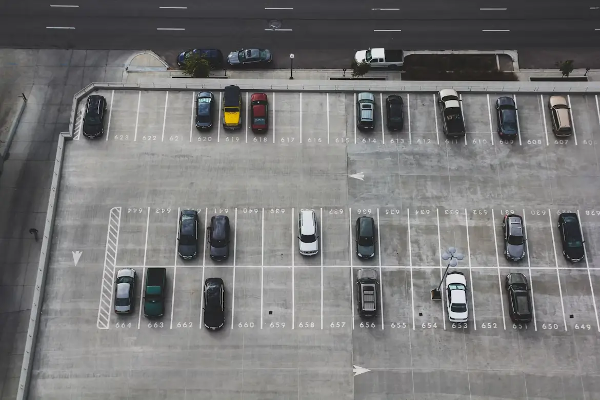 Aerial view of a mostly empty rooftop parking lot with a few scattered cars and visible numbered spaces.