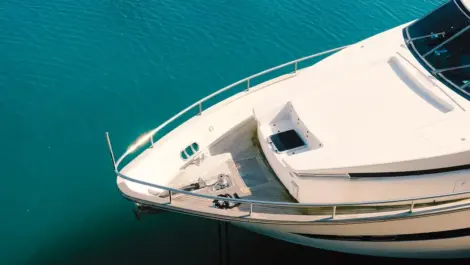 Close-up view of the front deck of a luxury white yacht floating on calm blue water.