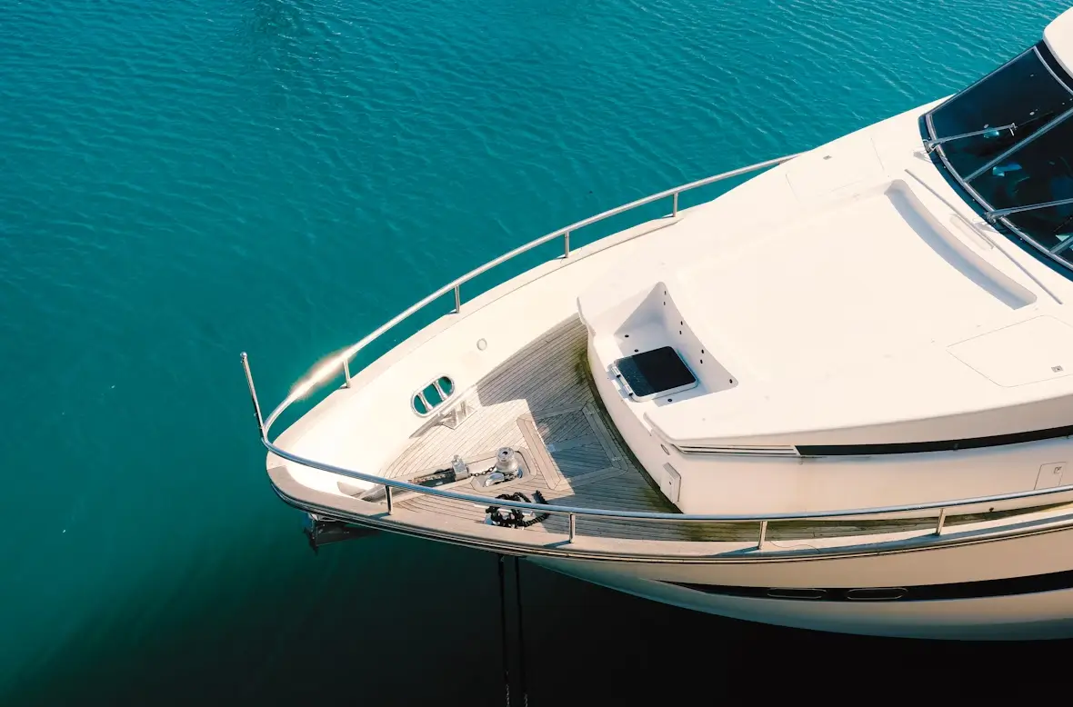 Close-up view of the front deck of a luxury white yacht floating on calm blue water.