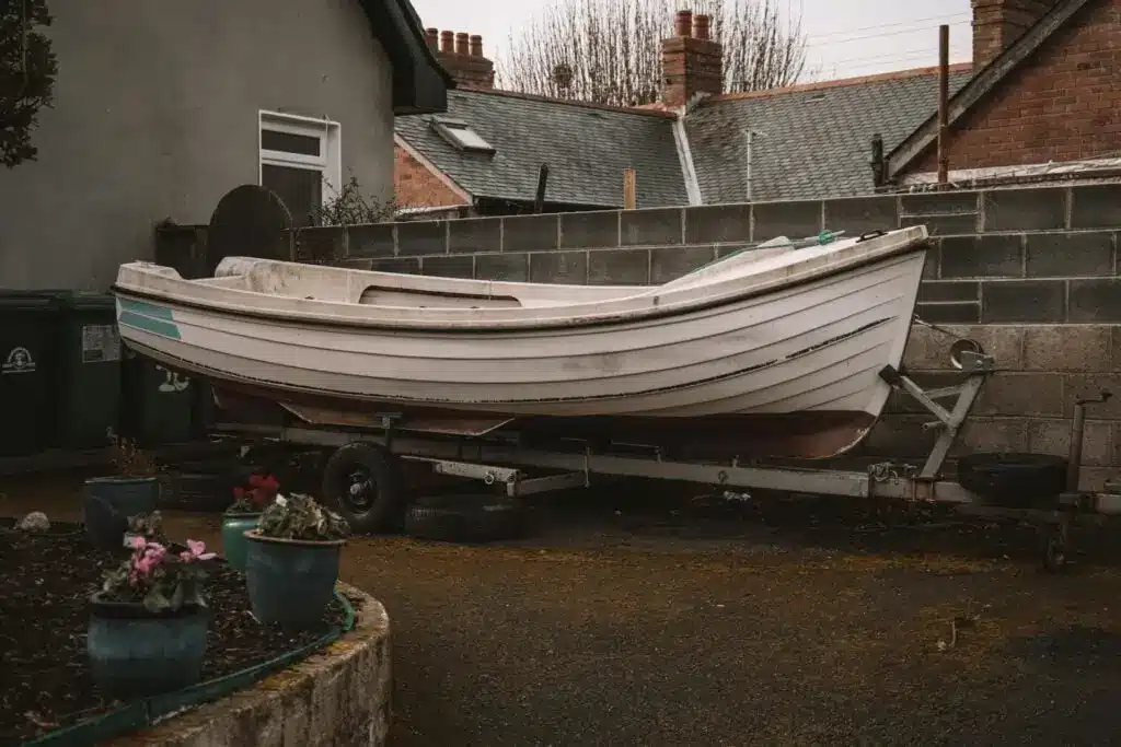 Unused boat being stored in the backyard of a house.