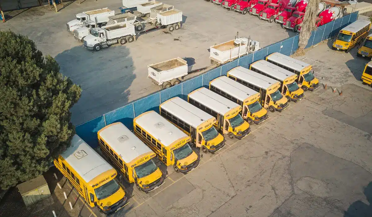 Aerial view of parked school buses and trucks in a lot.