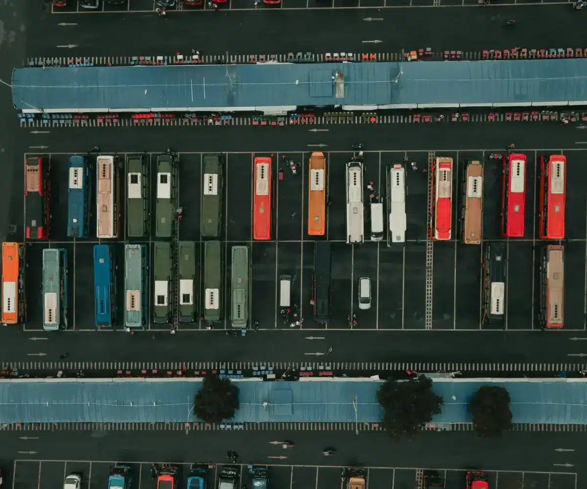 Aerial view of a parking lot with rows of colorful trucks parked under blue canopies.