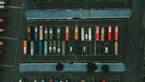 Aerial view of a parking lot with rows of colorful trucks parked under blue canopies.