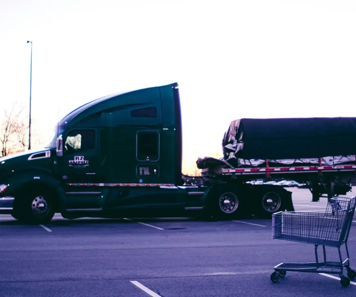 A semi-truck parked in a lot, with a shopping cart in the foreground.