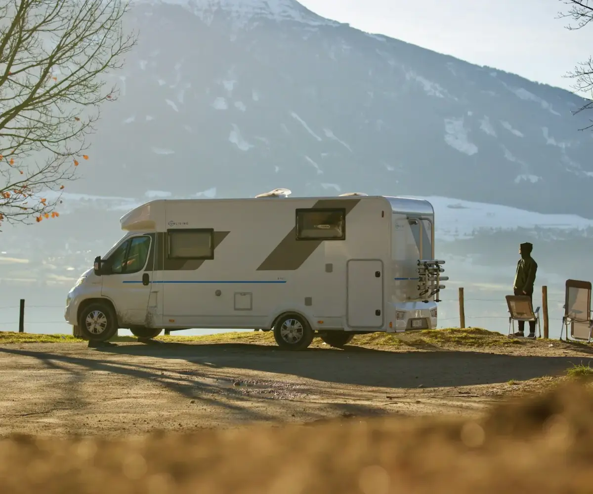 Camper parked with two people standing nearby enjoying the view.
