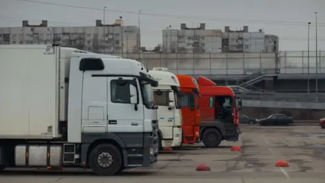 Parked trucks lined up in a lot near residential buildings.