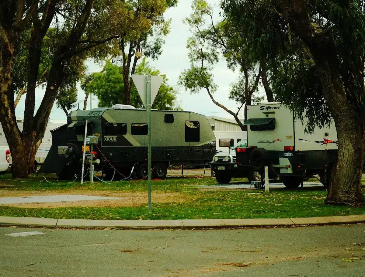 Multiple trailers parked at a shaded RV campground.