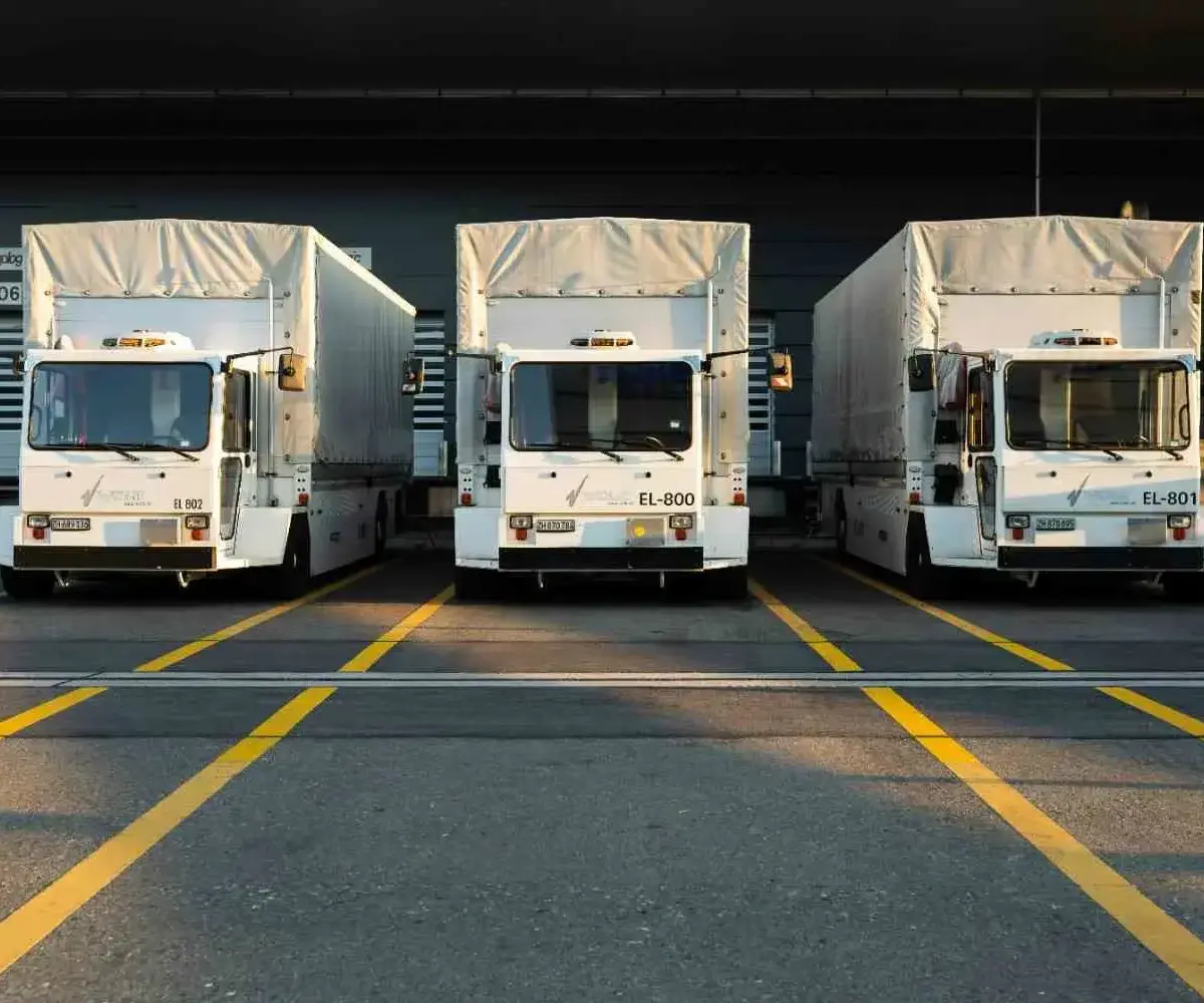 Three trucks parked at a loading dock with yellow lane markings.
