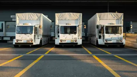 Three trucks parked at a loading dock with yellow lane markings.