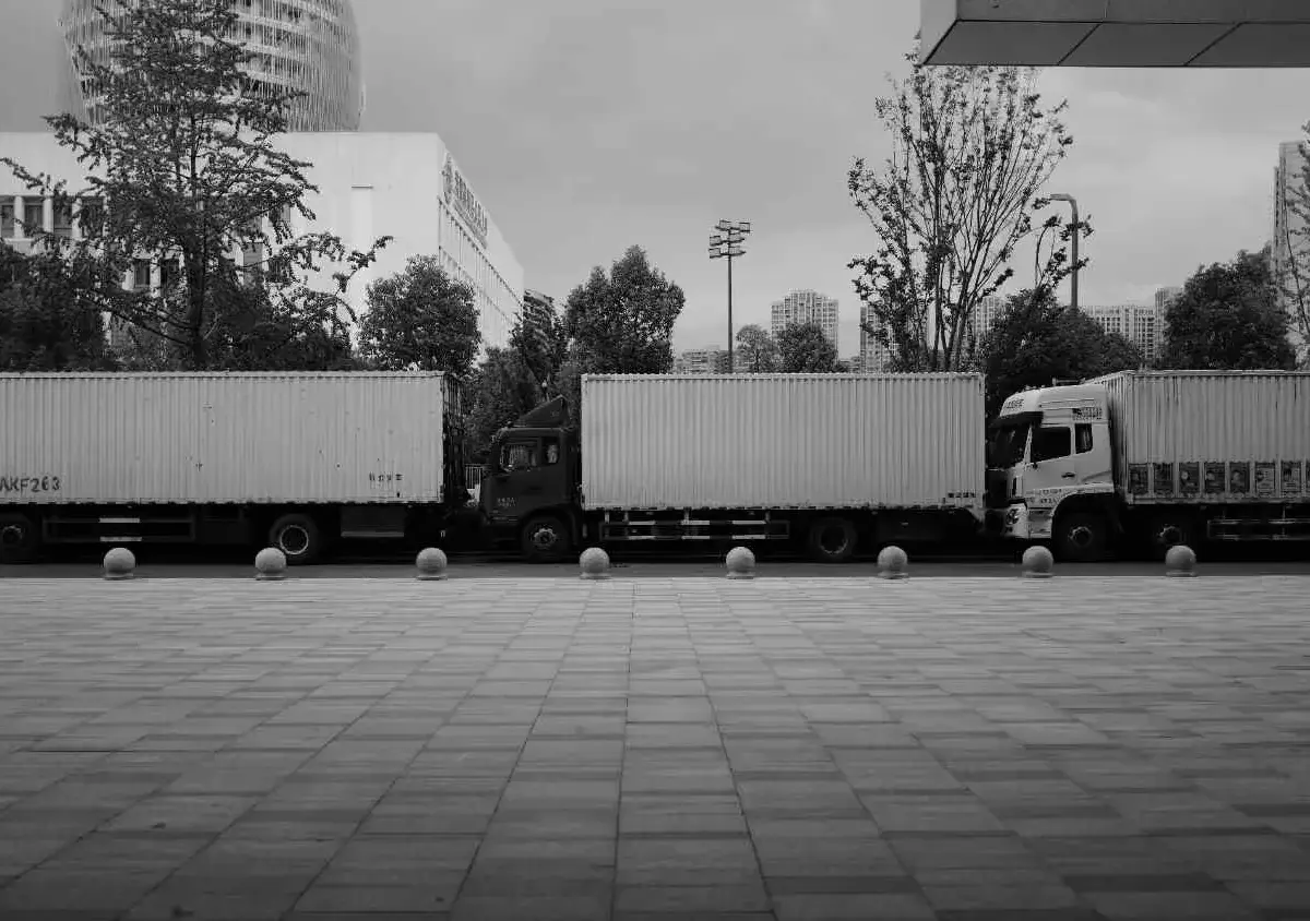 Three commercial trucks parked in a row outside an logistics facility.