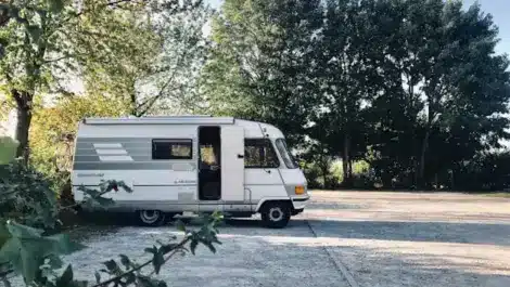 Vintage motorhome parked in a quiet, tree-lined lot.