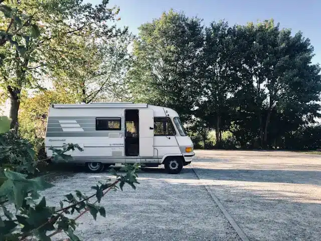 Vintage motorhome parked in a quiet, tree-lined lot.