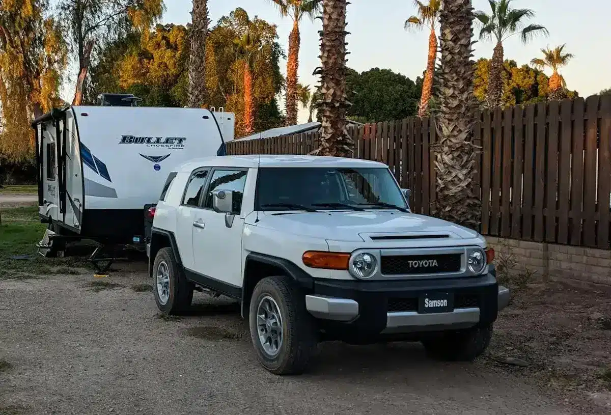 Travel trailer parked beside a white SUV in a campground.