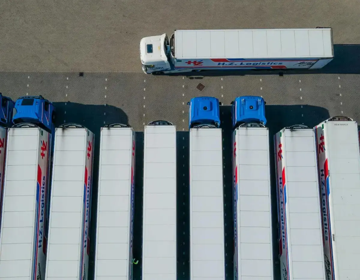 Aerial view of multiple trucks parked in a row with one truck maneuvering in the lot.