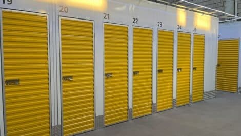 Row of indoor yellow storage unit doors in a well-lit facility.