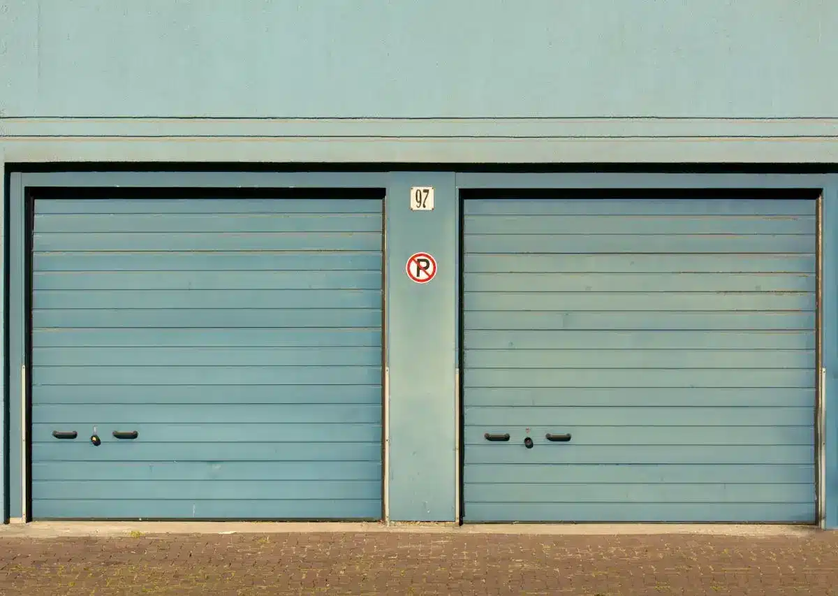 Two closed blue garage-style self storage units with a "no parking" sign in the middle, representing storage facilities as a potential investment option.