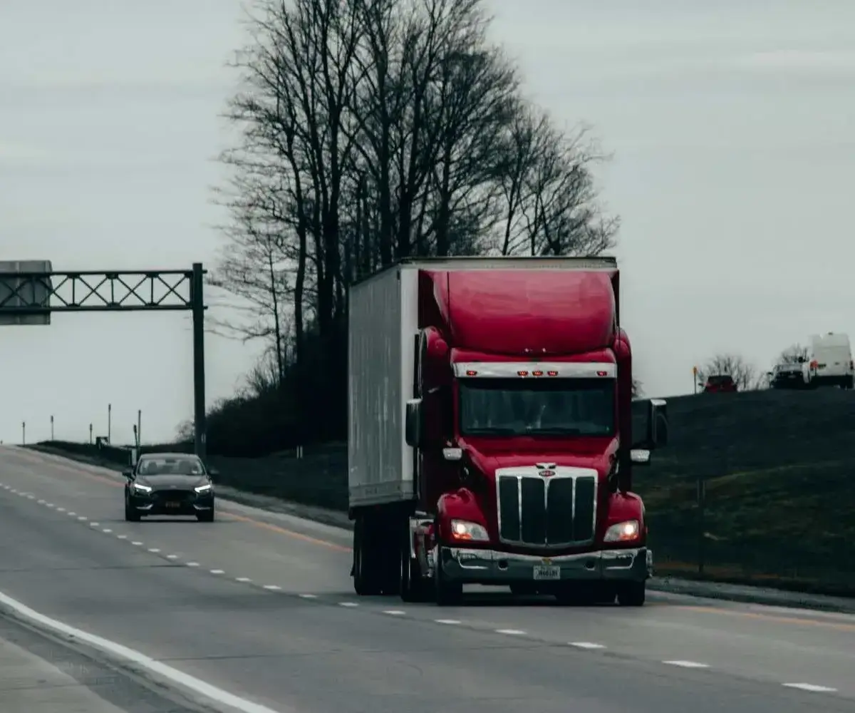 Red truck driving on a highway alongside passenger vehicles.