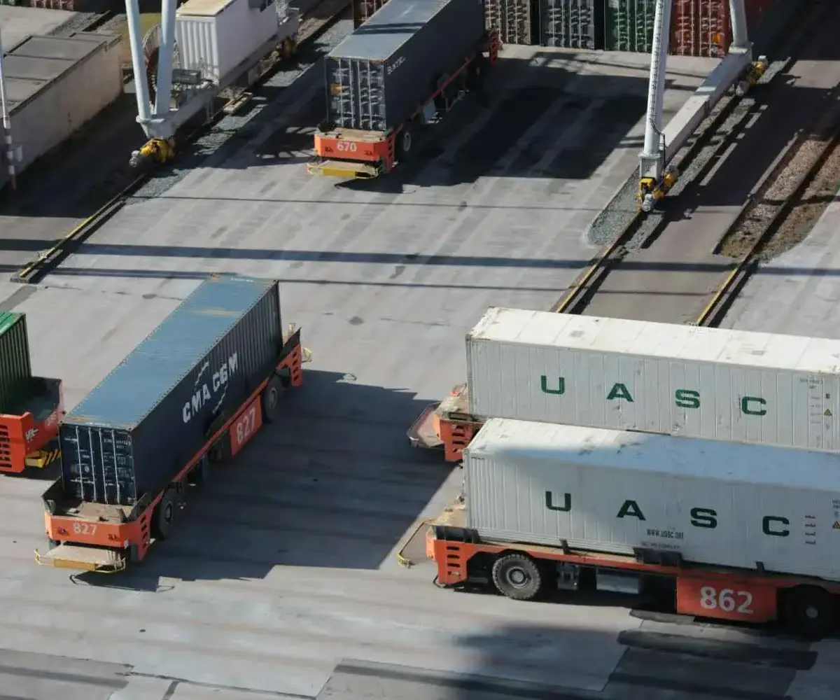 Container trucks moving cargo at a freight terminal.