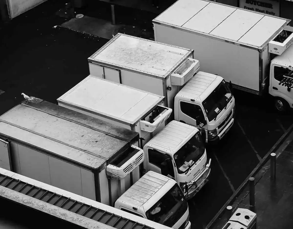 Overhead view of parked white box trucks in a city lot.
