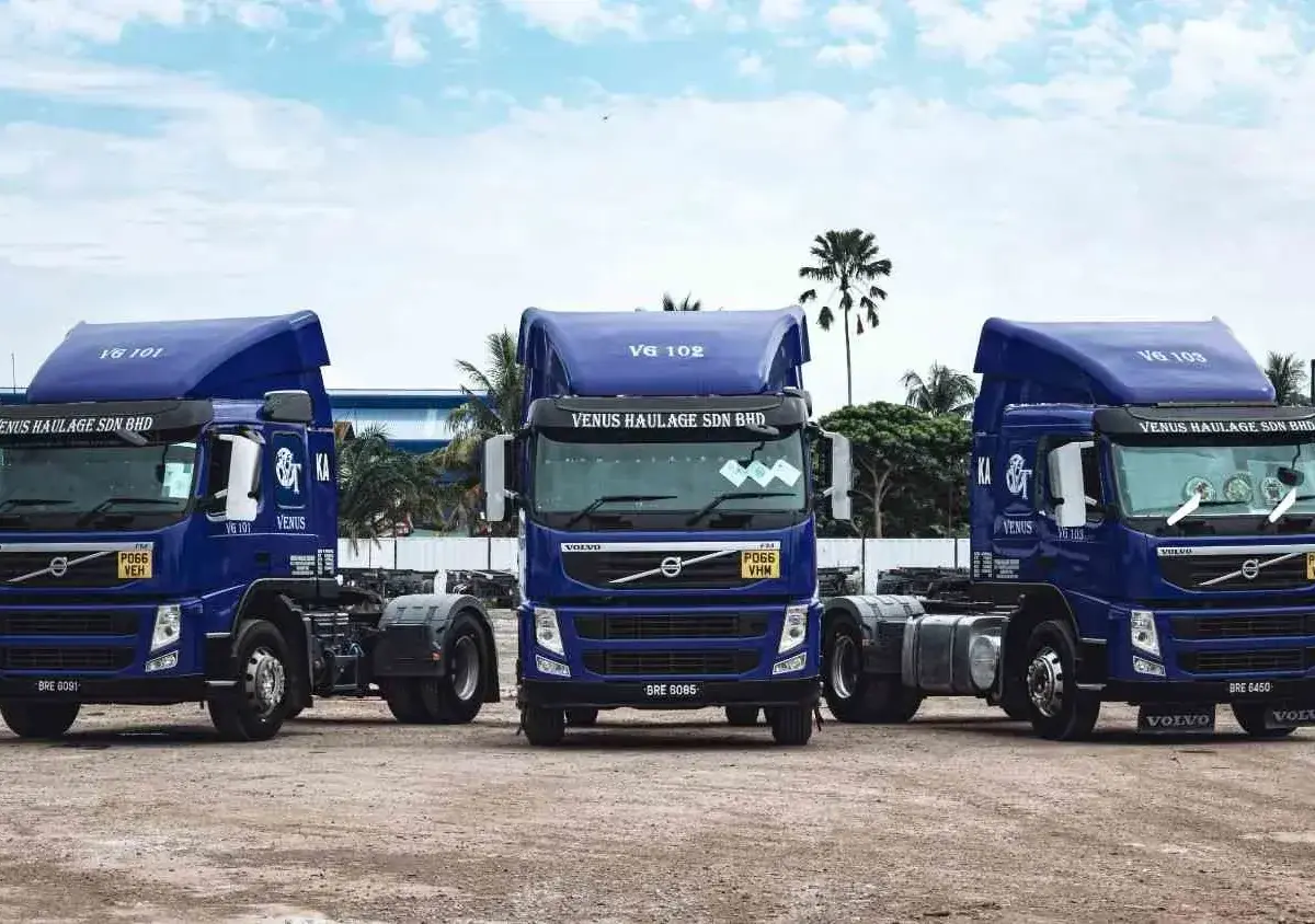 Three blue Volvo trucks parked side by side in a lot.