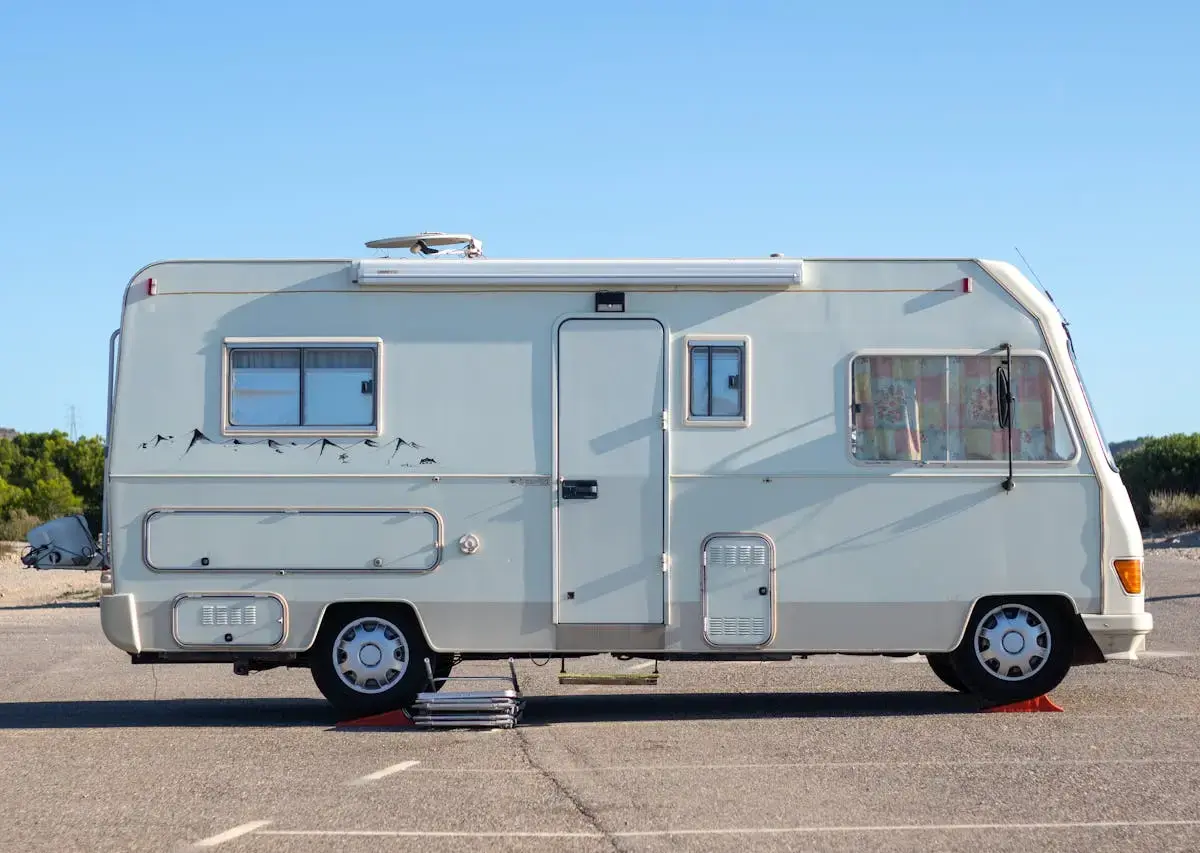 Parked motorhome on asphalt under clear blue sky.