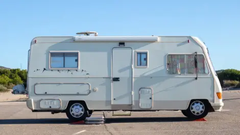 Parked motorhome on asphalt under clear blue sky.