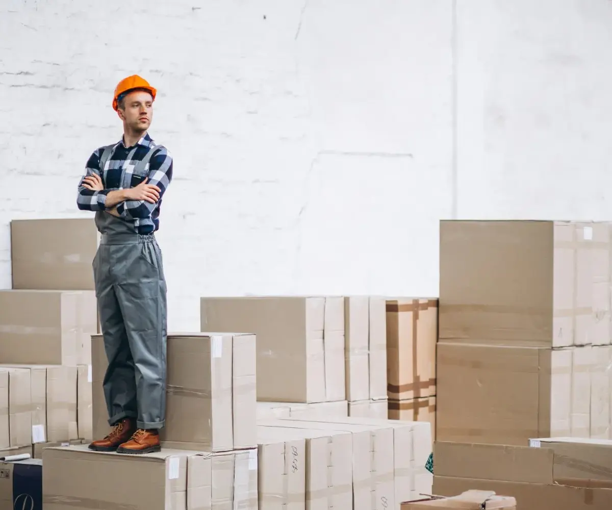 Contractor standing on stacked boxes in warehouse.