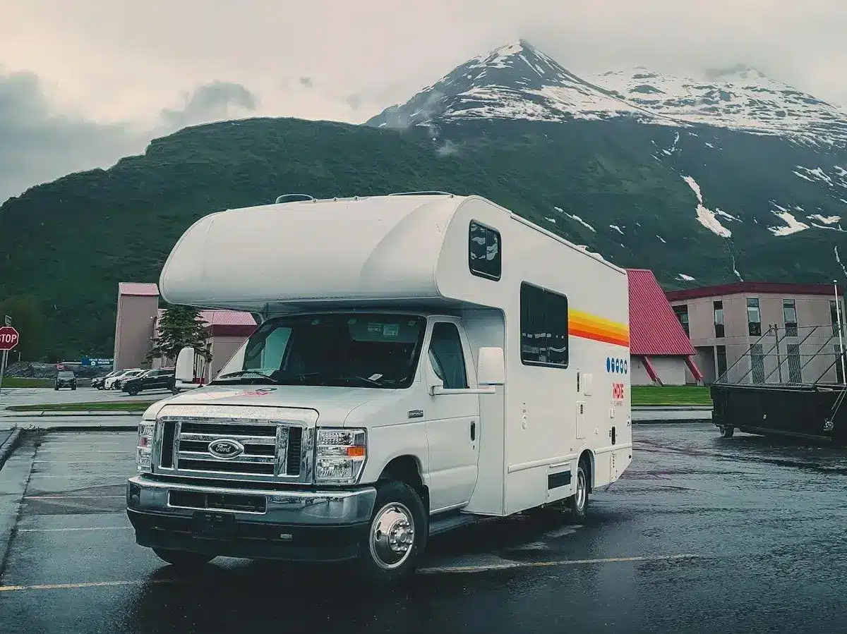 Class C RV parked in front of snowy mountain