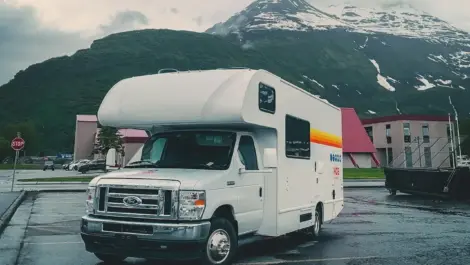 Class C RV parked in front of snowy mountain