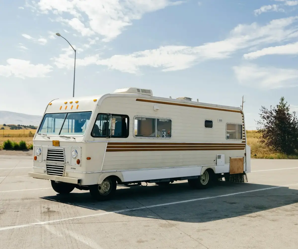 Vintage RV parked in an open lot on a sunny day.