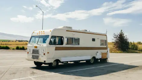 Vintage RV parked in an open lot on a sunny day.