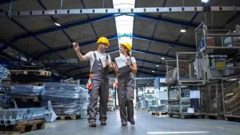 Factory employees inspecting materials in large warehouse