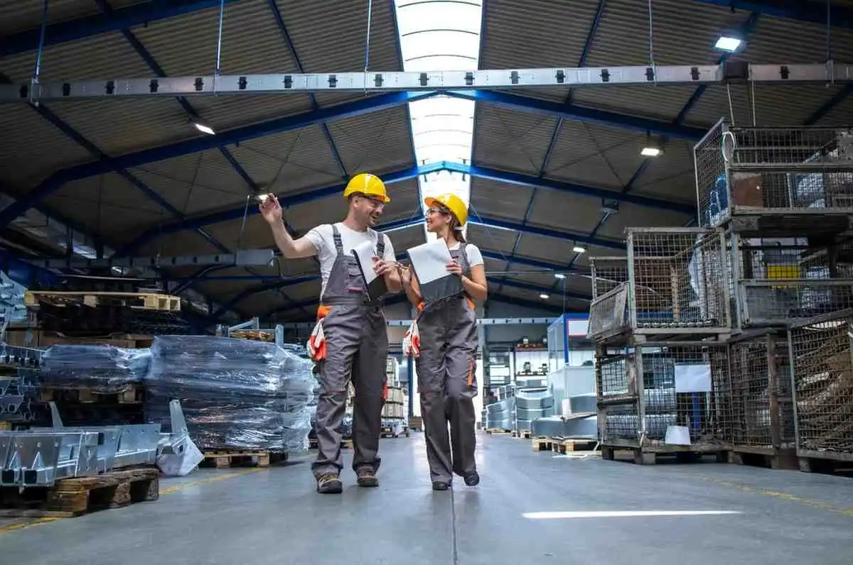 Factory employees inspecting materials in large warehouse