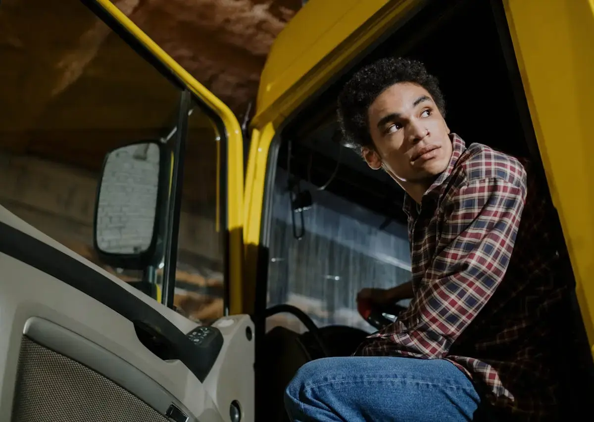 Driver sitting in a yellow truck, looking over his shoulder.