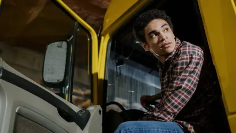 Driver sitting in a yellow truck, looking over his shoulder.