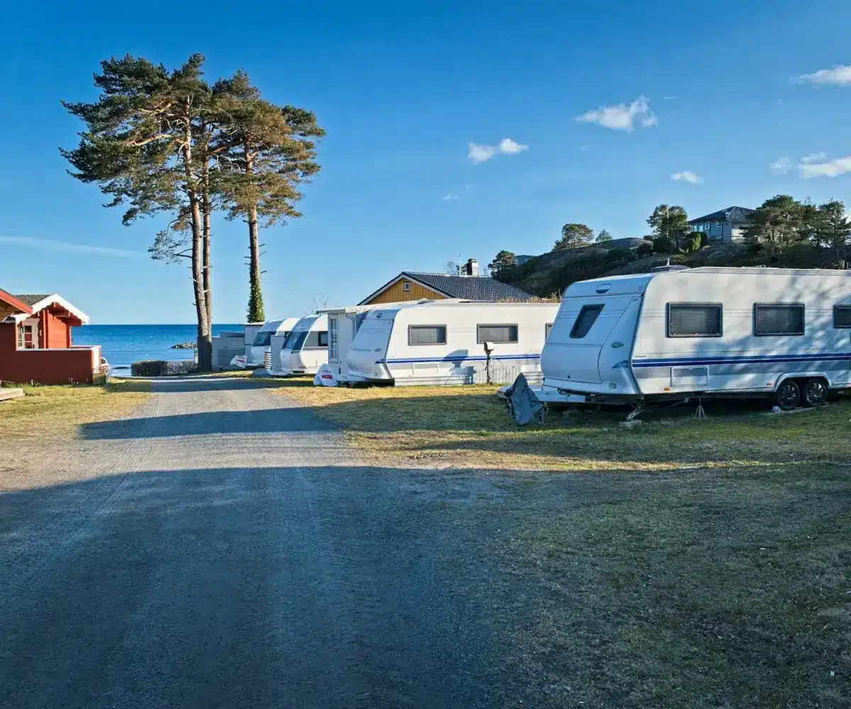 White travel trailers parked at a coastal campground under clear blue skies.