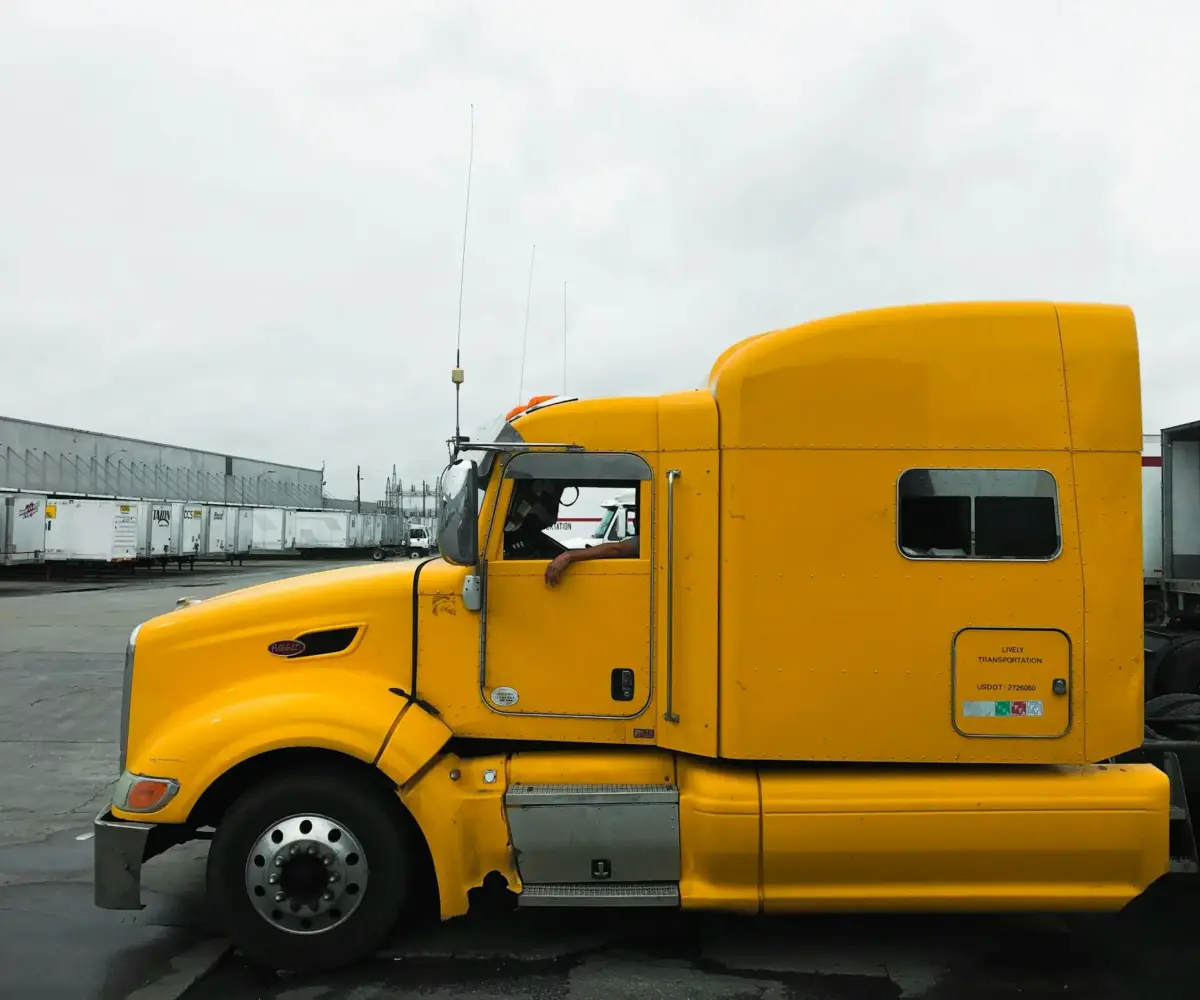 Bright yellow semi-truck cab parked in an industrial lot.